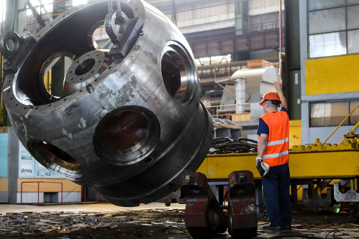 Worker in hi-vis beside heavy machinery on a factory floor