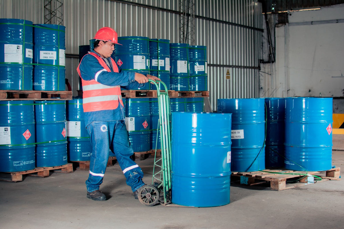 Worker in hi-vis moving a 205 litre drum on a drum truck in a drum store