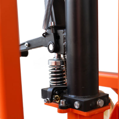 Close-up of a machine's hydraulic system, showcasing a spring, piston, and mechanical linkage in a sturdy orange frame.